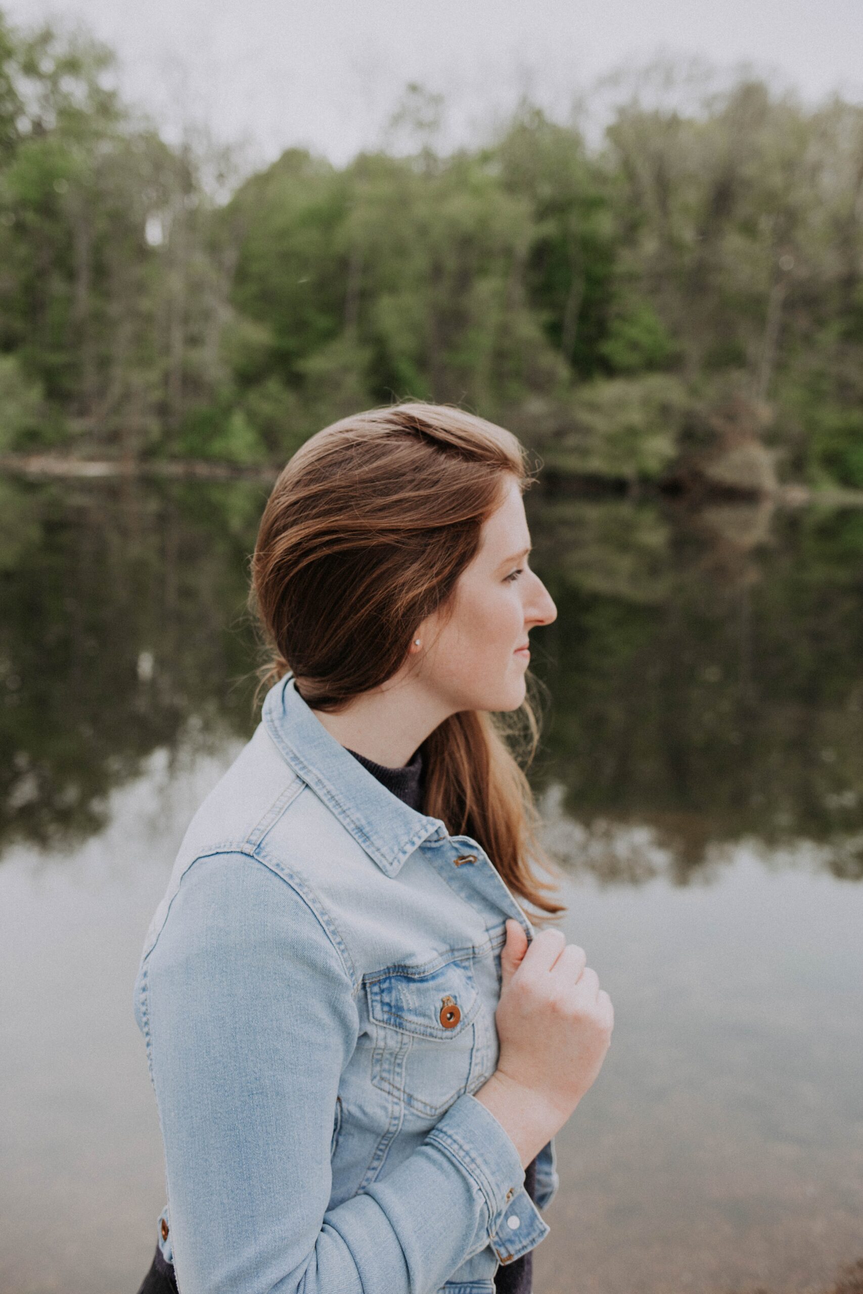 Woman by lake gazes thoughtfully